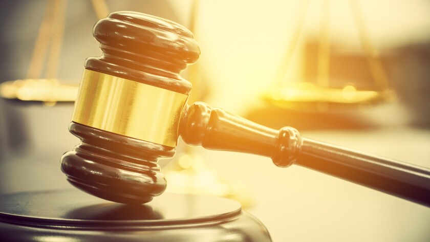 Legal office of lawyers, justice and law concept : Wooden judge gavel or a wood hammer and a soundboard used by a judge person on a desk in a courtroom with a blurred brass scale of justice behind.