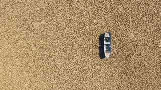Aerial view of a fishing boat on a drought dry lakebed.