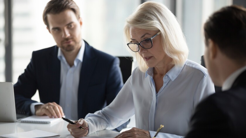 Concentrated aged businesswoman checking agreement before signing