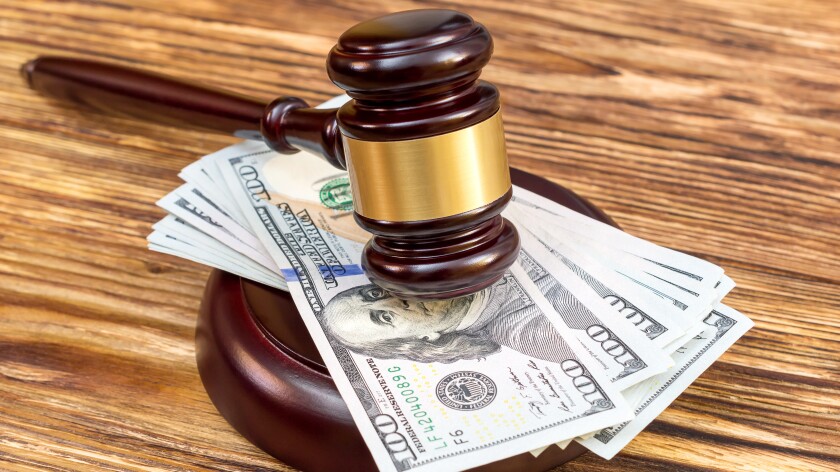 Judge's gavel and stand with US dollar bills on the wooden table.