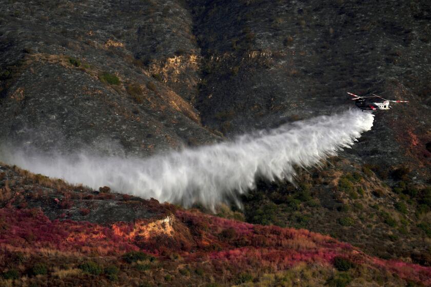 Water is dropped onto the Franklin Fire by helicopter, Wednesday, Dec. 11, 2024, in Malibu, Calif. (AP Photo/Eric Thayer)