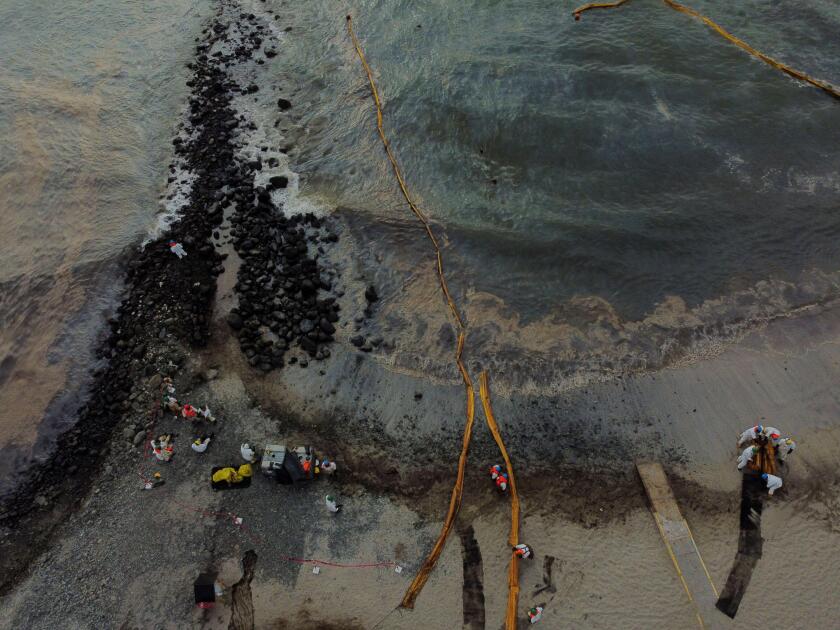Workers clean the beach near Repsol's La Pampilla refinery after the recent oil spill that has caused an ecological disaster on the coast of Lima, in Ventanilla, Peru January 29, 2022. Picture taken with a drone January 29, 2022. REUTERS/Angela Ponce
