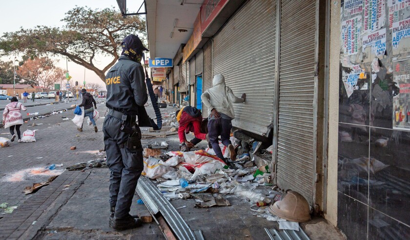 (210712) -- JOHANNESBURG, July 12, 2021 (Xinhua) -- A police officer deals with protesters looting a shop in Johannesburg, South Africa, on July 12, 2021. Soldiers have been deployed in KwaZulu-Natal and Gauteng provinces to deal with violent protests and